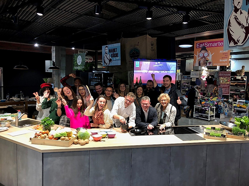 Gruppe von Influencer:innen bei Food-Reise-Event in moderner Showküche mit frischen Zutaten